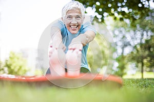 Senior woman doing yoga and legs stretching  in the park