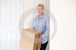 Senior Woman Downsizing In Retirement Carrying Boxes Into New Home On Moving Day photo