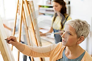 Senior woman drawing on easel at art school studio