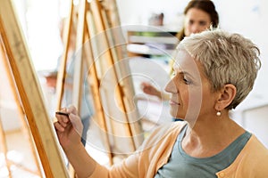 Senior woman drawing on easel at art school studio