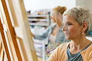 Senior woman drawing on easel at art school studio