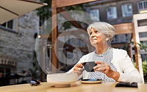 Senior woman drinking coffee at street cafe