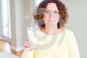 Senior woman drinking a glass of fresh milk with a confident expression on smart face thinking serious