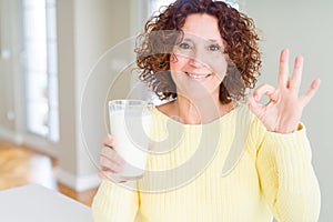 Senior woman drinking a glass of fresh milk doing ok sign with fingers, excellent symbol