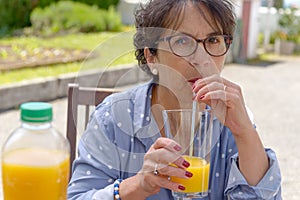 Senior woman drinking orange juice in her garden