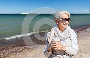 Senior woman drinking takeaway coffee on beach