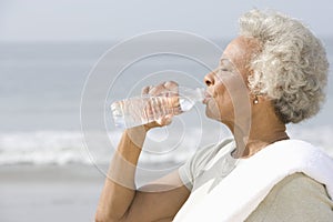 Senior Woman Drinking Water At Beach photo