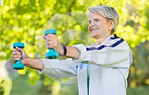 Senior woman with dumbbells exercising at park