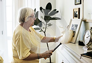 Senior woman dusting a family photo frame