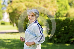 Senior woman with earphones running in summer park