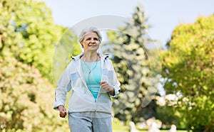 Senior woman with earphones running in summer park