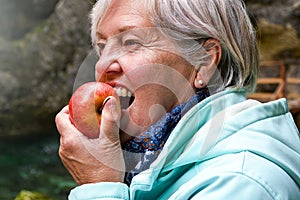 Senior woman eating apple outside in the park