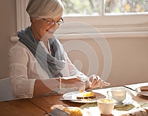 Senior, woman and eating breakfast in home with bread, cheese and tea with happiness by table in the morning. Elderly