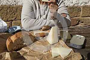 A senior woman, eats slices of goat cheese, Spain