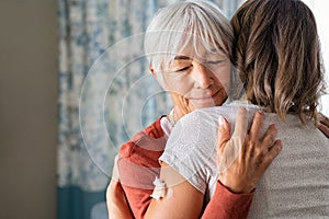 Senior woman embracing daughter after covid immunization vaccine