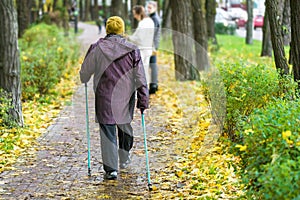 Senior woman enjoying nordic walking at beautiful colorful autumn park. Old age person doing pole walk excercise