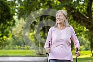 Senior woman enjoying nordic walking exercise in a lush green park