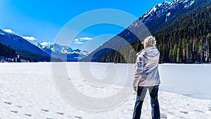 Senior woman enjoying the view of frozen Duffey Lake iin BC Canada