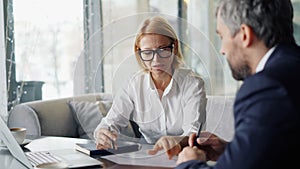 Senior woman entrepreneur negotiating contract with business partner in cafe