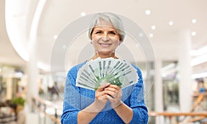 Senior woman with euro money over shopping mall