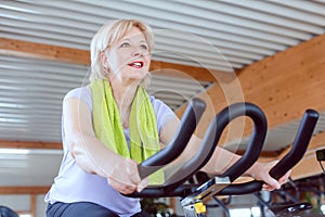 Senior woman on an exercise bike in the gym