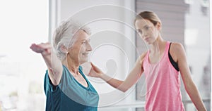 Senior woman, exercise and instructor for yoga, class and help from personal trainer, fitness or studio. Active, pilates