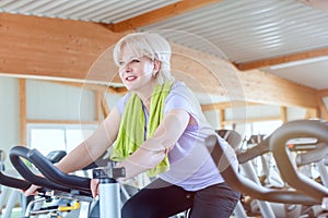 Senior woman exercising for better fitness on a bike in the gym