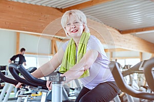 Senior woman exercising for better fitness on a bike in the gym