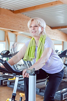 Senior woman exercising for better fitness on a bike in the gym