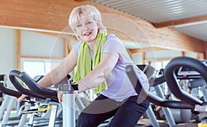 Senior woman exercising for better fitness on a bike in the gym