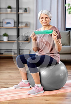 senior woman exercising with elastic band at home