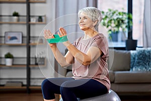 senior woman exercising with elastic band at home