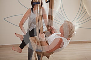 Senior woman exercising at with fly yoga trainer