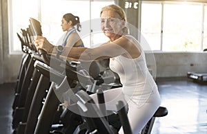 Senior woman exercising spinning bike in fitness gym. elderly