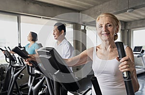 Senior woman exercising spinning bike in fitness gym. elderly healthy lifestyle concept