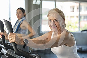 Senior woman exercising spinning bike in fitness gym. elderly healthy lifestyle concept