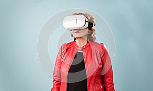 Senior woman experiencing virtual reality while using VR glasses over an isolated background.