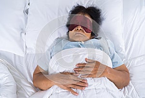 Senior woman with eye mask sleeping on a bed