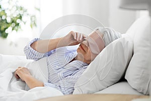 senior woman with eye sleeping mask in bed at home