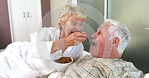 Senior woman feeding her husband