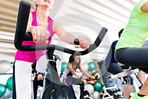 Senior Woman at Fitness Spinning on bike in gym