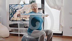 Senior woman on fitness toning ball stretching resistance band