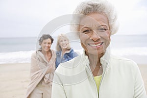 Senior Woman In Fleece Jacket With Friends On Beach