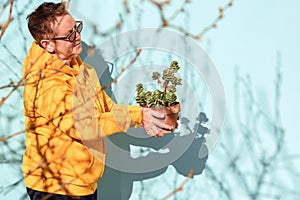 Senior woman florist working at her small business - standing with flower pot and smiling.