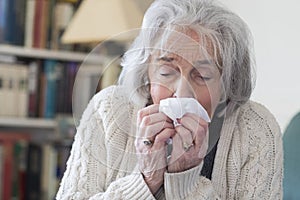 Senior Woman With Flu Blowing Nose At Home