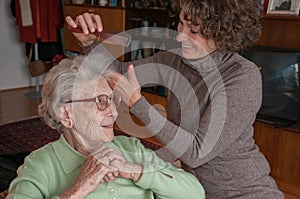 Senior Woman Gets Hair Styled By Caregiver 