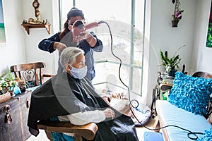 Senior woman getting a haircut at home during Covid-19 pandemic wearing face mask