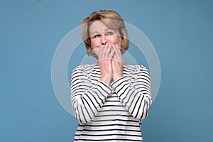 Senior woman giggle covering mouth with hands. Gossip concept.