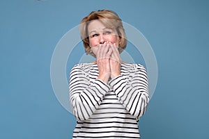 Senior woman giggle covering mouth with hands. Gossip concept. photo