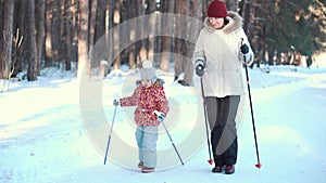 Senior woman and girl nordic walking in winter park